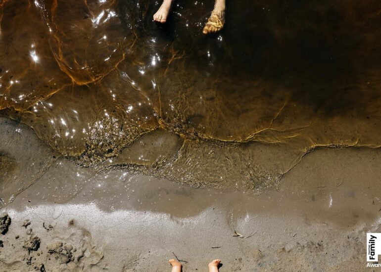 Füße von einem Kind und von einer Puppe am Wasser