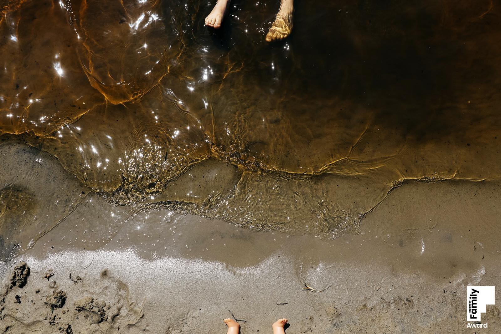 Füße von einem Kind und von einer Puppe am Wasser